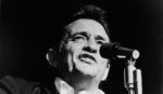 Headshot of American country singer Johnny Cash (1932 - 2003) singing on stage in a still from the film, 'Johnny Cash - The Man, His World, His Music,' directed by Robert Elfstrom, 1969.