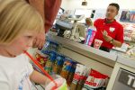 PEMBROKE PINES, FL - JULY 18: Assistant manager Engel Mozo rings up a sale, as 3-year-old Samantha Krass sips on her Slurpee at a 7-Eleven store on July 18, 2002 in Pembroke Pines, Florida. 7-Eleven, Inc., the premiere name and largest chain in the convenience retailing industry, is observing its 75th anniversary in 2002. (Photo by Joe Raedle/Getty Images)
